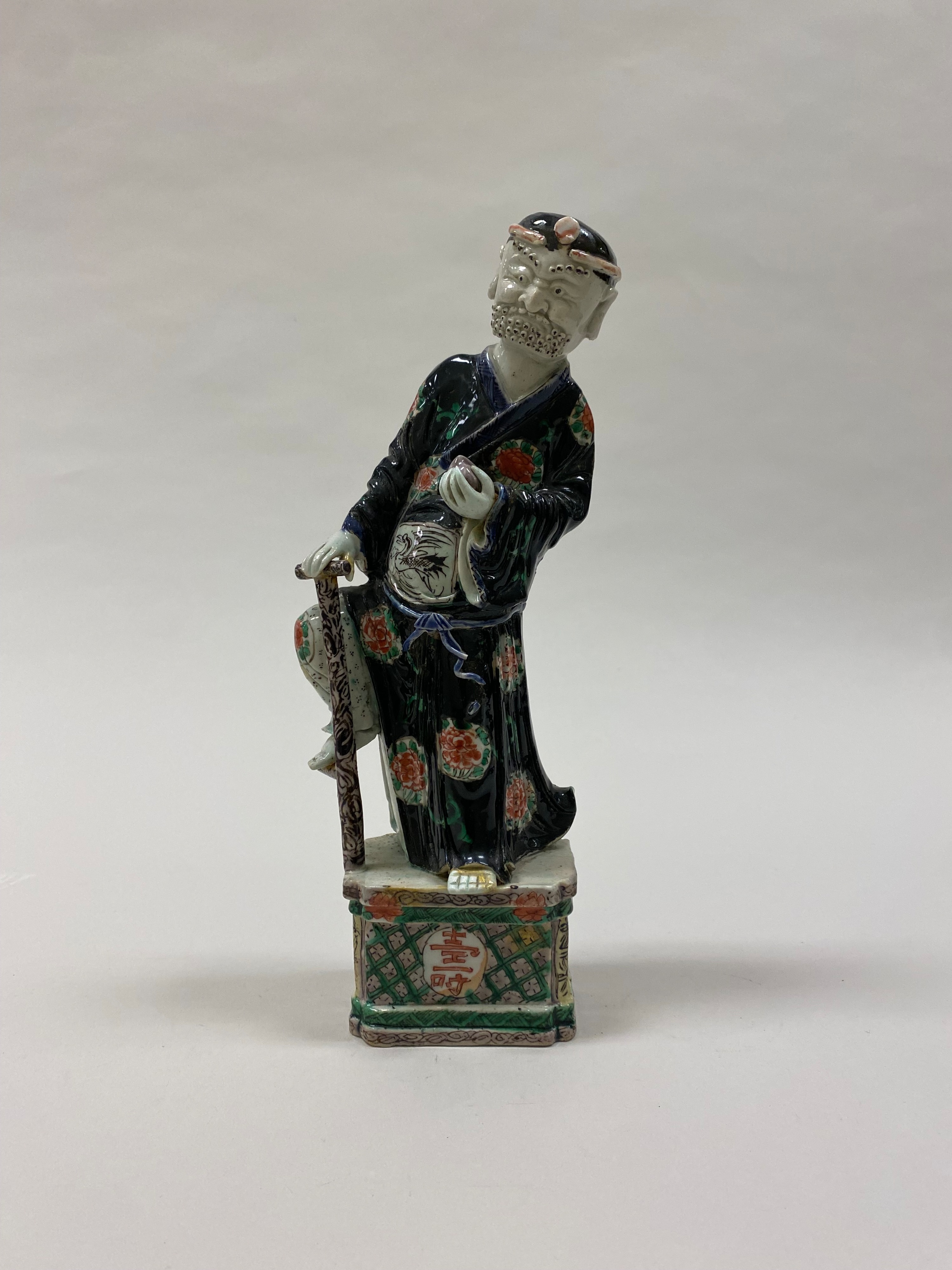 Polychrome ceramic figure of Li Tieguai carrying his crutch and gourd.